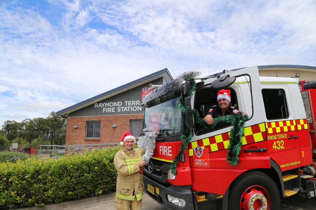 FA LA LA: Raymond Terrace Fire and Rescue deputy captain Giacomo Arnott and firefighter Brett Hedley decking out the fire truck ahead of the Christmas lolly run on December 19. Picture: Ellie-Marie Watts