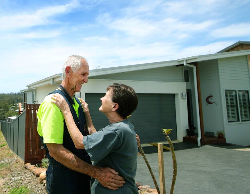 Wayne and Gail Duncombe embrace in front of their new home in Conjola Park. Picture: Sylvia Liber 