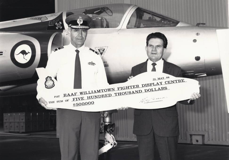 Air Commodore Trevor Richardson receives a cheque from Minister for Transport and Communications Support Peter Morris. Picture supplied